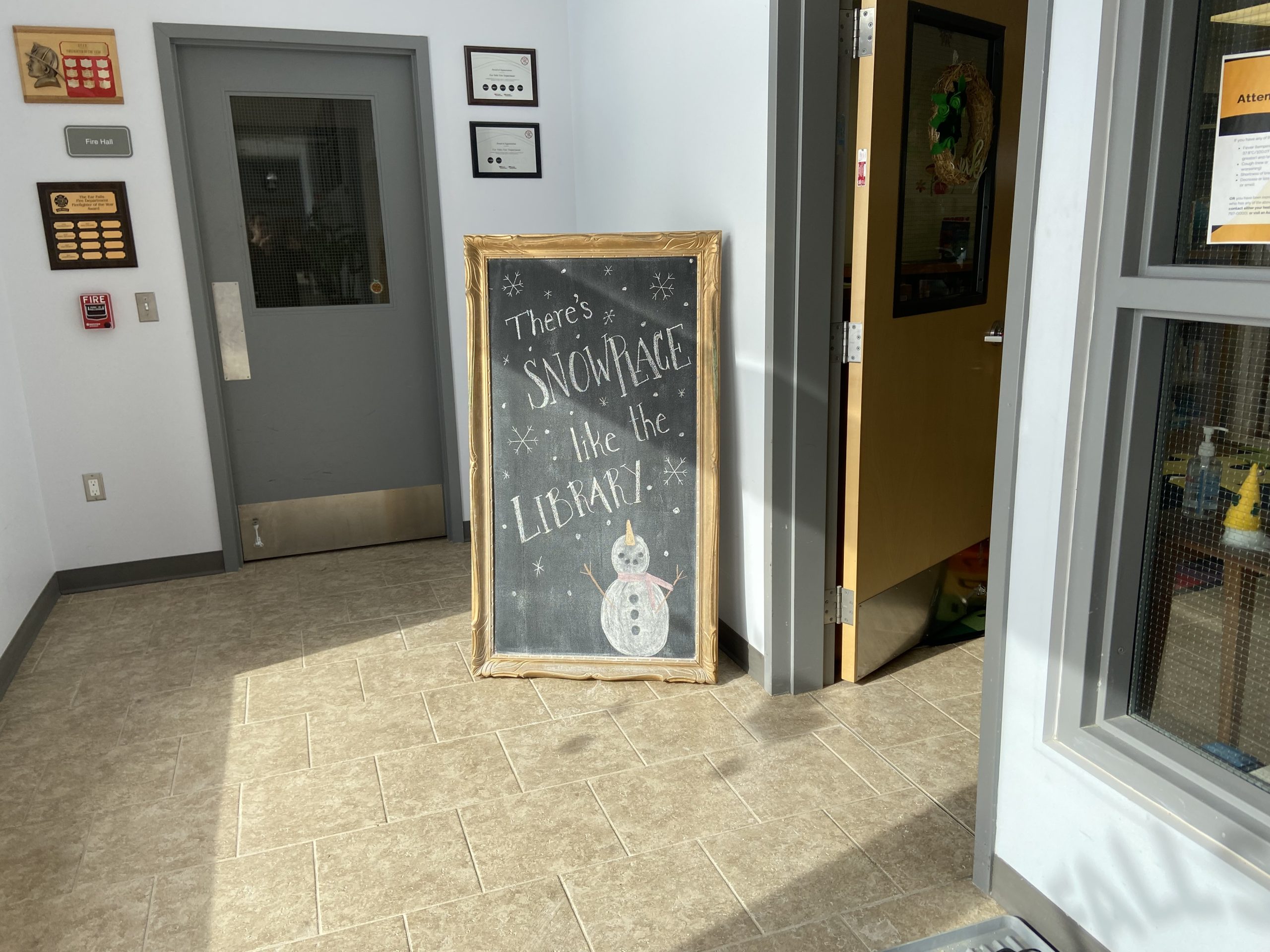 A view of one of the chalkboard drawings often displayed in the front of the library. THis one reads "There's SNOW PLACE like the LIBRARY!" with a drawing of a snowman underneath.